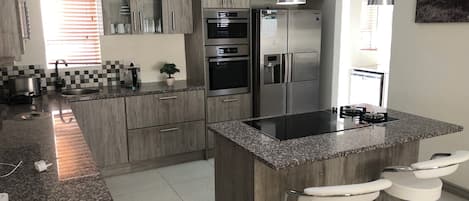A modern kitchen with granite countertops, stainless steel appliances, and a central island with bar stools.