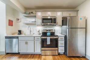 Une cuisine moderne dotée d’appareils électroménagers en acier inoxydable, de meubles de rangement en bois et d’un plancher en bois.