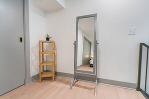 Un couloir avec une étagère en bois, un miroir et une porte donnant sur une autre pièce.