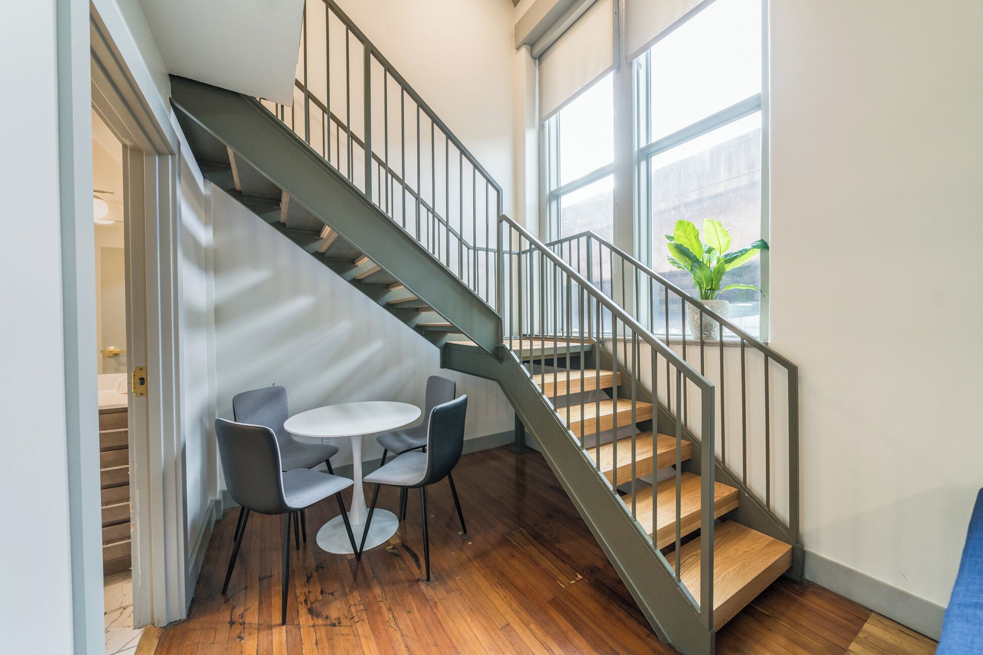 Un escalier avec une rampe en métal menant à un palier où se trouvent une table ronde et deux chaises.