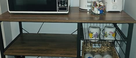 A kitchen counter with a microwave, toaster, and a basket of paper towels.