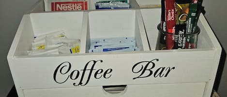 Una caja blanca con la etiqueta 'Coffee Bar' que contiene diversos productos y envases de café.