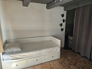 A single-bed room with a white headboard, a small bedside table, and a storage drawer. - A Provençal stone farmhouse dating from 1870, with a terrace and a pool. (Mougins)