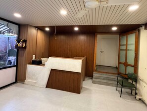 Una recepción con detalles de madera, un estante con adornos y vistas al exterior a través de un ventanal.