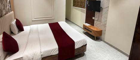 Une chambre d’hôtel avec un lit, une table de chevet en bois, un téléviseur et un sol en marbre.