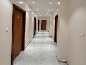 Un pasillo con puertas de madera, paredes blancas y suelo de baldosas.