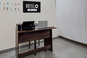 Ein Hotelrezeptionstresen mit Drucker, Laptop und einem Schild mit der Aufschrift 'HOTEL OYO-Serviced'.
