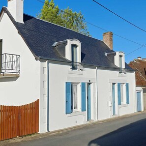 A two-story white building with blue shutters, a wooden fence, and a clear sky. - Charming Riverside Gite in the Brenne National Park close to amenities. (Belabre)