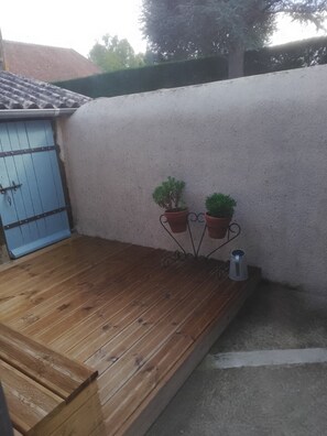 A wooden deck with a blue door, potted plants, and a metal stand. - Charming Riverside Gite in the Brenne National Park close to amenities. (Belabre)