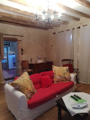 Ein Wohnzimmer mit einem roten Sofa, einer Kristallleuchtre und einem Essbereich mit einem Holztisch.