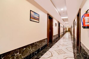 Ein Hotelgang mit Marmorboden, Holztüren und einem Feuerlöscher an der Wand.