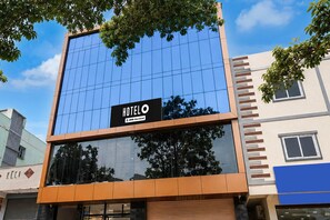 Un hôtel moderne avec une façade en verre, une enseigne indiquant qu’il est géré par OYO, et une entrée bien visible avec un auvent marron.