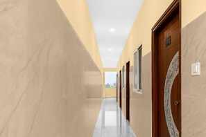 A corridor with marble walls, wooden doors, and a ceiling with recessed lighting. - Deluxe Lavish Stays (Hyderabad)