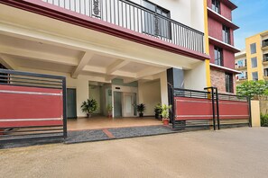 A building entrance with a gated driveway, potted plants, and a clear sky.