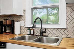 A kitchen with a double sink, a coffee maker, and two soap dispensers. - Modern 3BR, Sleeps 9, Mins to Arrowhead & KC (Raytown)