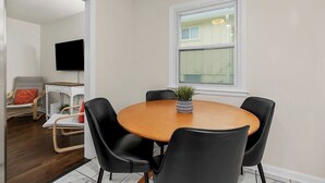 Un comedor con una mesa redonda, sillas negras y una planta en maceta.