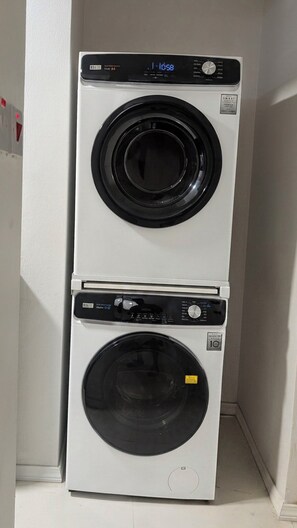 A stacked washer and dryer unit with a digital display and control panel. - Central Retreat (Kingston)