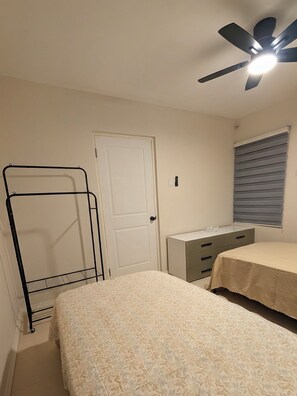 A bedroom with a bed, a dresser, a door, and a ceiling fan. - Central Retreat (Kingston)