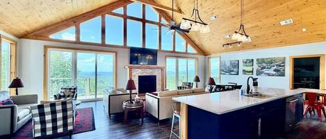 A spacious living area with a large window, a fireplace, and a kitchen with a central island.