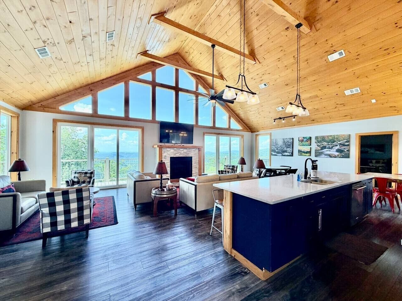A spacious living area with a large window, a fireplace, and a kitchen with a bar area.