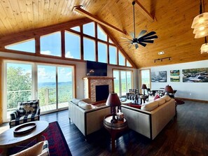 Un amplio salón con chimenea, ventanas grandes y un techo alto.
