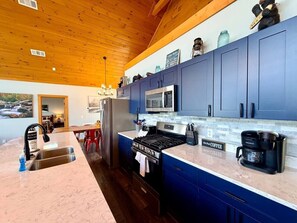 Eine Küche mit blauen Schränken, einem Edelstahlkühlschrank, einem Herd und einer Kaffeemaschine.