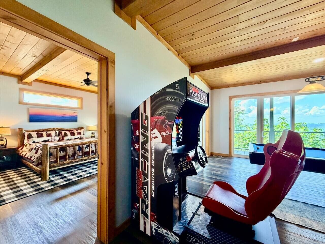A room with a racing simulator setup, a checkered floor, a sofa, and a view through large windows.