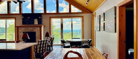 A spacious dining area with a long wooden table, red chairs, and a view of the outdoors through large windows.