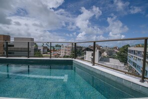 Ein Pool auf dem Dach mit freiem Blick auf die umliegenden Gebäude und den Himmel.