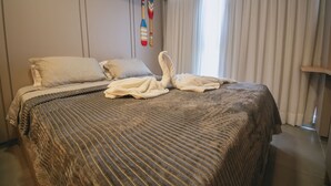 A hotel room with a bed, pillows, a blanket, and a towel laid out on the bed. - Luxury studio apartment 3 minutes from the natural pools (Ipojuca)