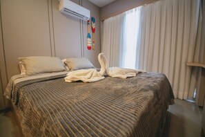 Ein Hotelzimmer mit einem Bett, Kissen, einer Decke und einem Handtuch, das auf dem Bett drapiert ist.