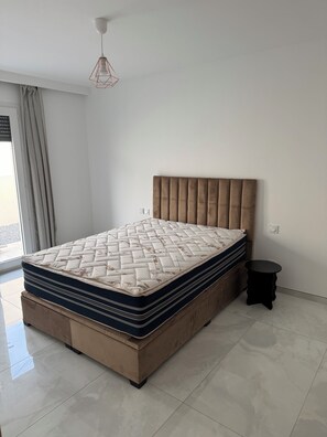 Une chambre à coucher avec un grand lit, une table de chevet et un luminaire suspendu.