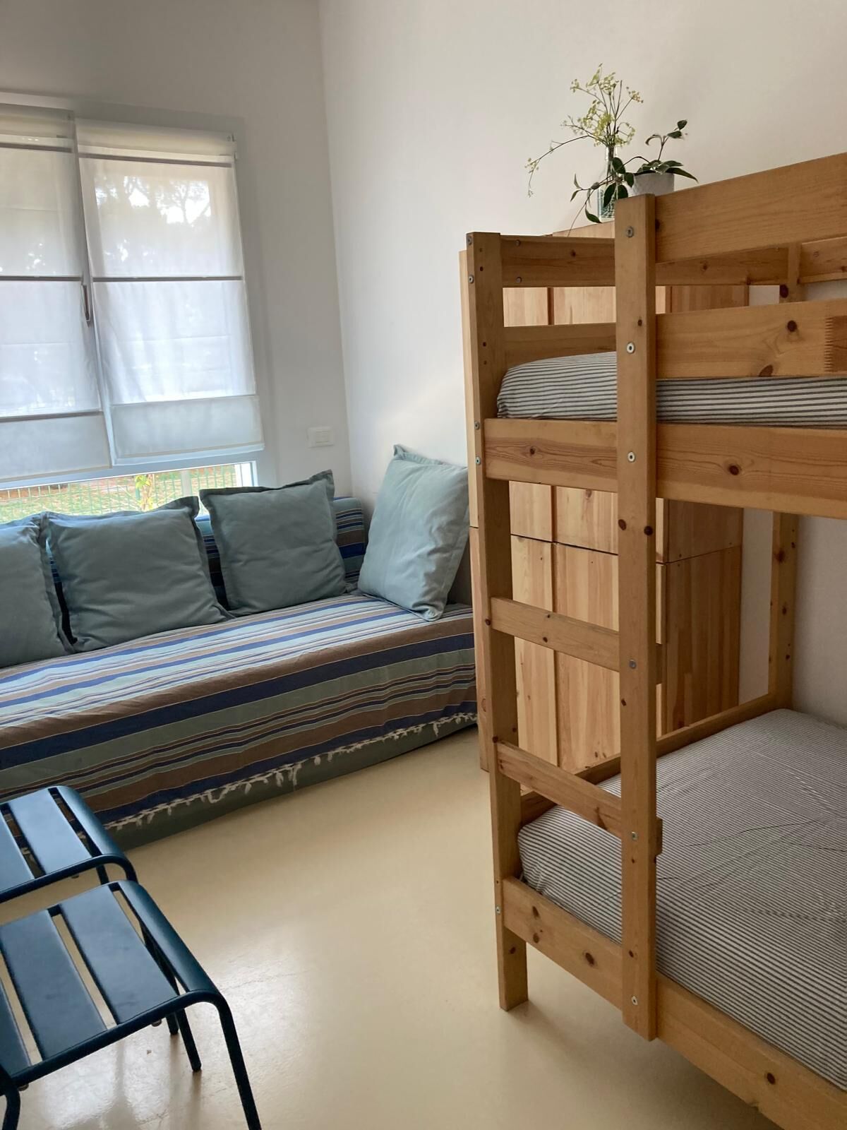 Ein Stockbett mit Holzbalken, ein gestreiftes Sofa mit Kissen und ein kleiner Tisch.