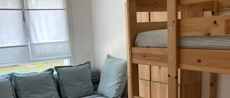Ein Stockbett mit Holzbalken, ein gestreiftes Sofa mit Kissen und ein kleiner Tisch.