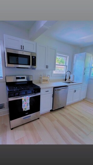 Una cucina moderna con mobili bianchi, piano cottura in acciaio inossidabile, forno a microonde ed elettrodomestici.