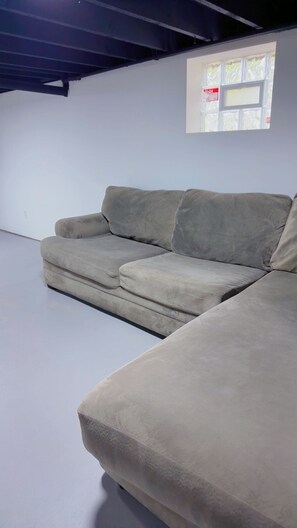 Ein graues Sofa in einem Zimmer mit weißen Wänden und einem Fenster.