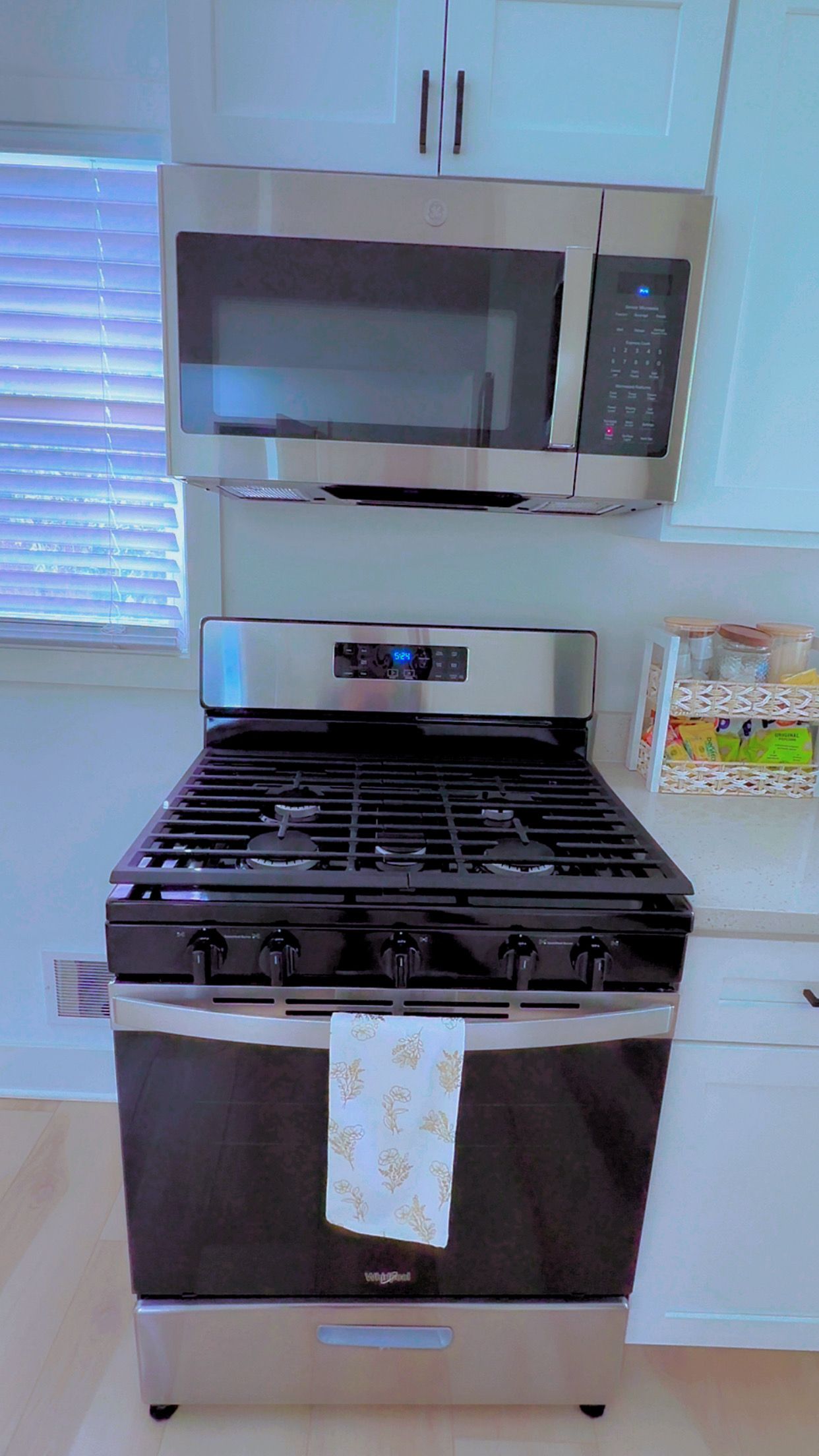 A kitchen with a stainless steel stove, a microwave above it, and a white cabinet.