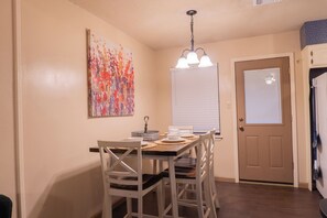 A dining area with a table set for four, a ceiling light fixture, and a door with a window. - Cozy 2-bedroom townhome in beautiful Lawton with AC (Lawton)