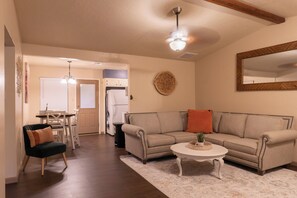 A living room with a sofa, a coffee table, and a dining area with a table and chairs. - Cozy 2-bedroom townhome in beautiful Lawton with AC (Lawton)