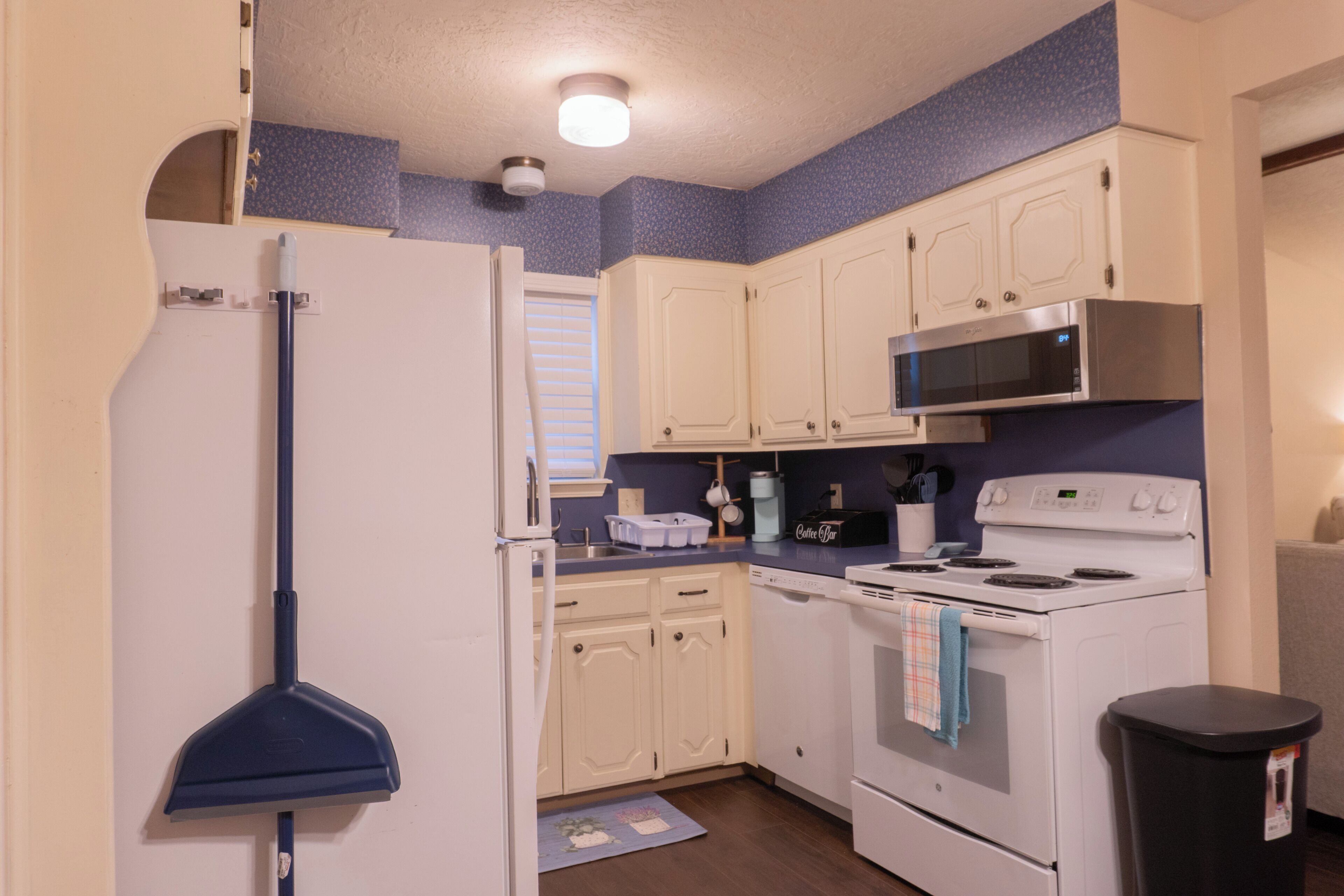 A compact kitchen with white cabinets, a microwave, a stove, and a refrigerator.
