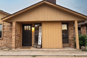 A two-story building with a brown facade, a black front door, and a 'HELLO' sign. - Cozy 2-bedroom townhome in beautiful Lawton with AC (Lawton)