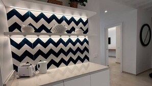 A modern kitchen with a white countertop, a zigzag patterned backsplash, and built-in cabinets. - De Vivo Realty - Panorama Suite Sorrento (Sorrento)