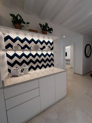 A modern kitchen with a white countertop, a zigzag patterned backsplash, and built-in cabinets. - De Vivo Realty - Panorama Suite Sorrento (Sorrento)