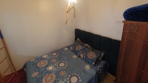 Et soveværelse med en seng, et skab og en hængende lampe.