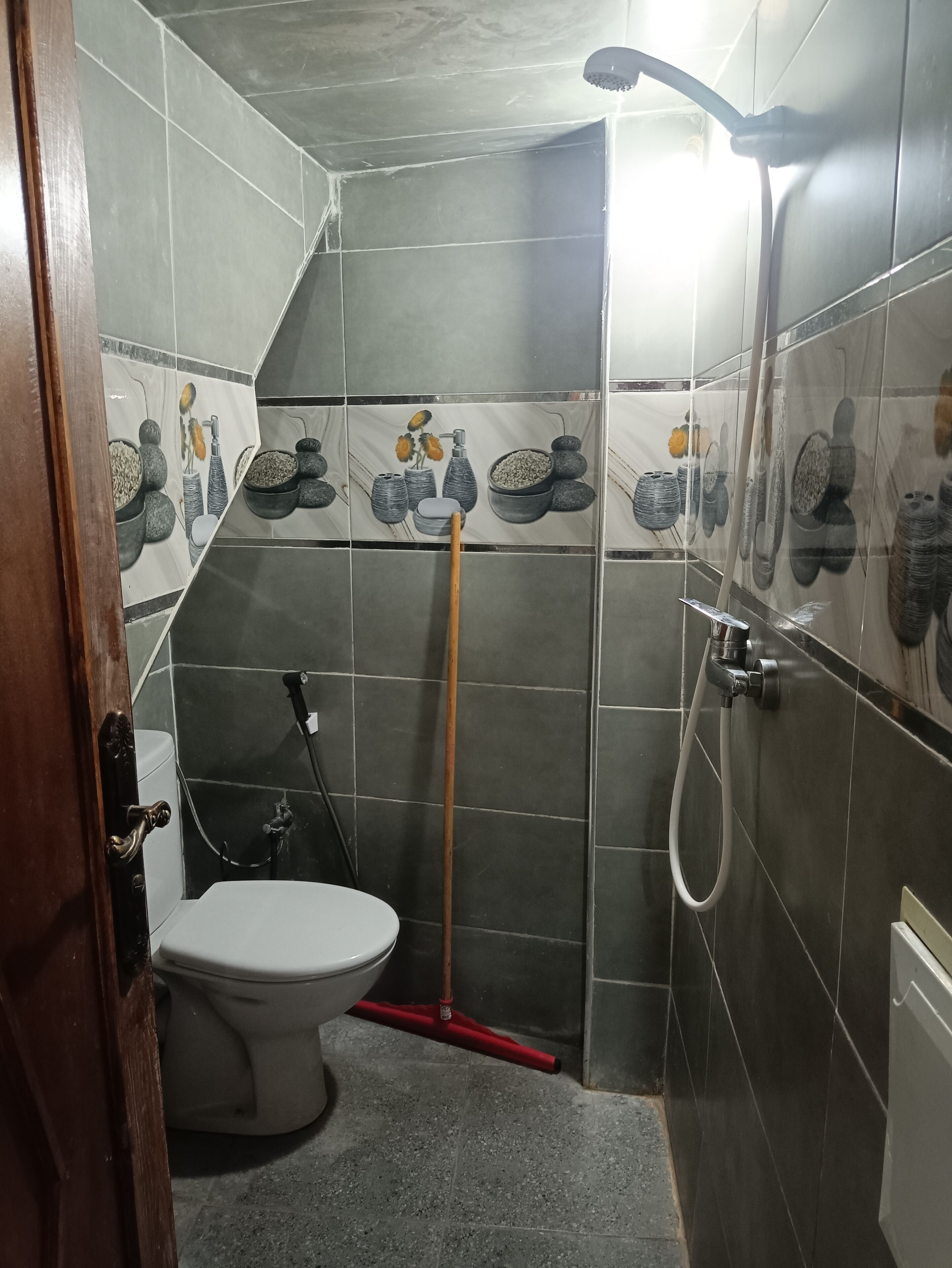 A bathroom with a toilet, shower, and tiled walls.