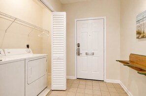 Un espace buanderie comprenant un lave-linge, un étendoir et une porte avec une boîte aux lettres.