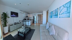 A modern living room with a sofa, a coffee table, and a TV. There is a kitchen area with a fridge and a bar. - Beautifull Condo Apartament With sea View Morros Sonesta (Cartagena)