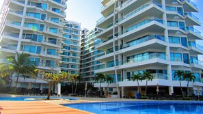 A multi-story hotel with balconies, a swimming pool, and palm trees. - Beautifull Condo Apartament With sea View Morros Sonesta (Cartagena)