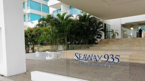 A modern building with a glass facade, outdoor seating area, and a sign for 'SEAWAY 935 CARTAGENA.' - Beautifull Condo Apartament With sea View Morros Sonesta (Cartagena)