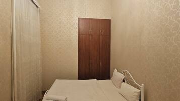 Un dormitorio con cama, armario y mesita de noche.